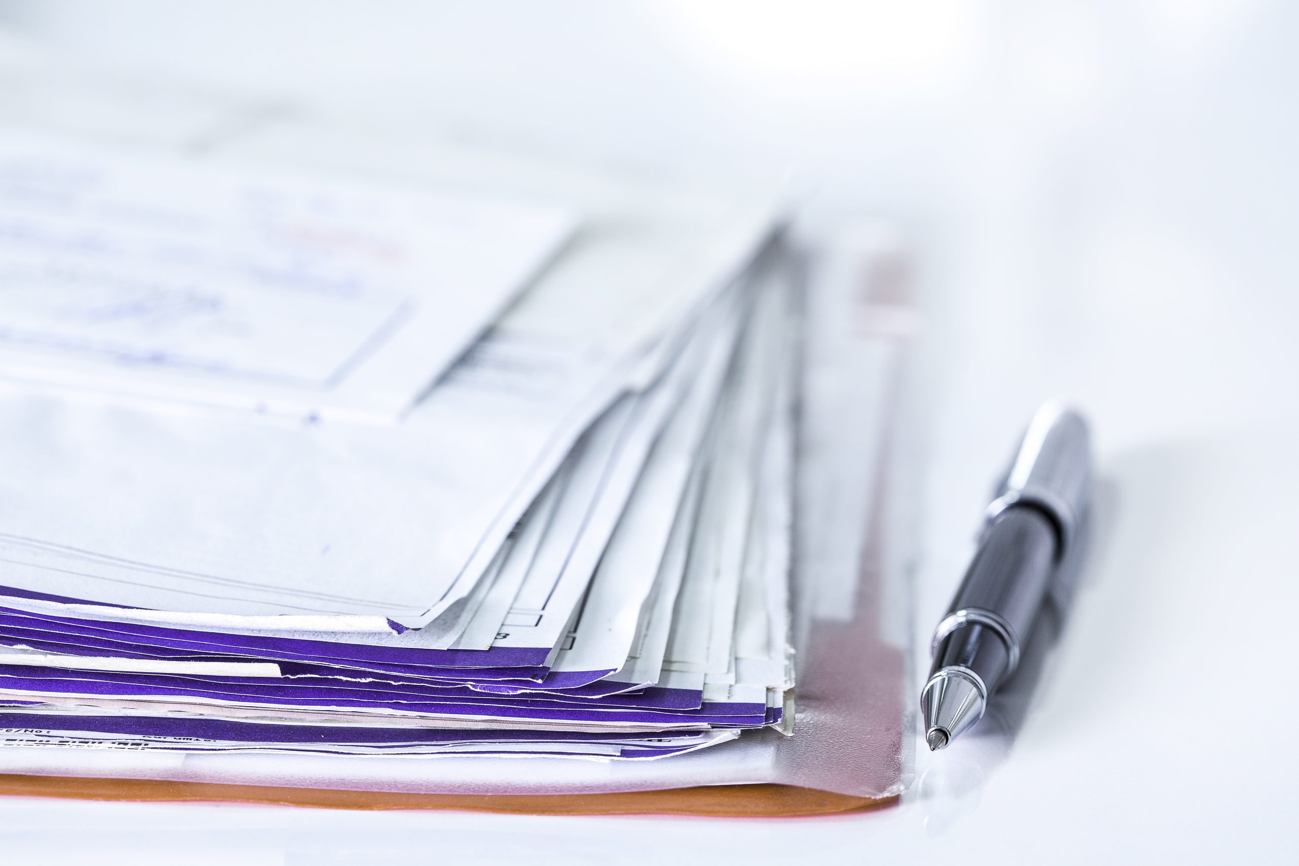a stack of bills and a pen