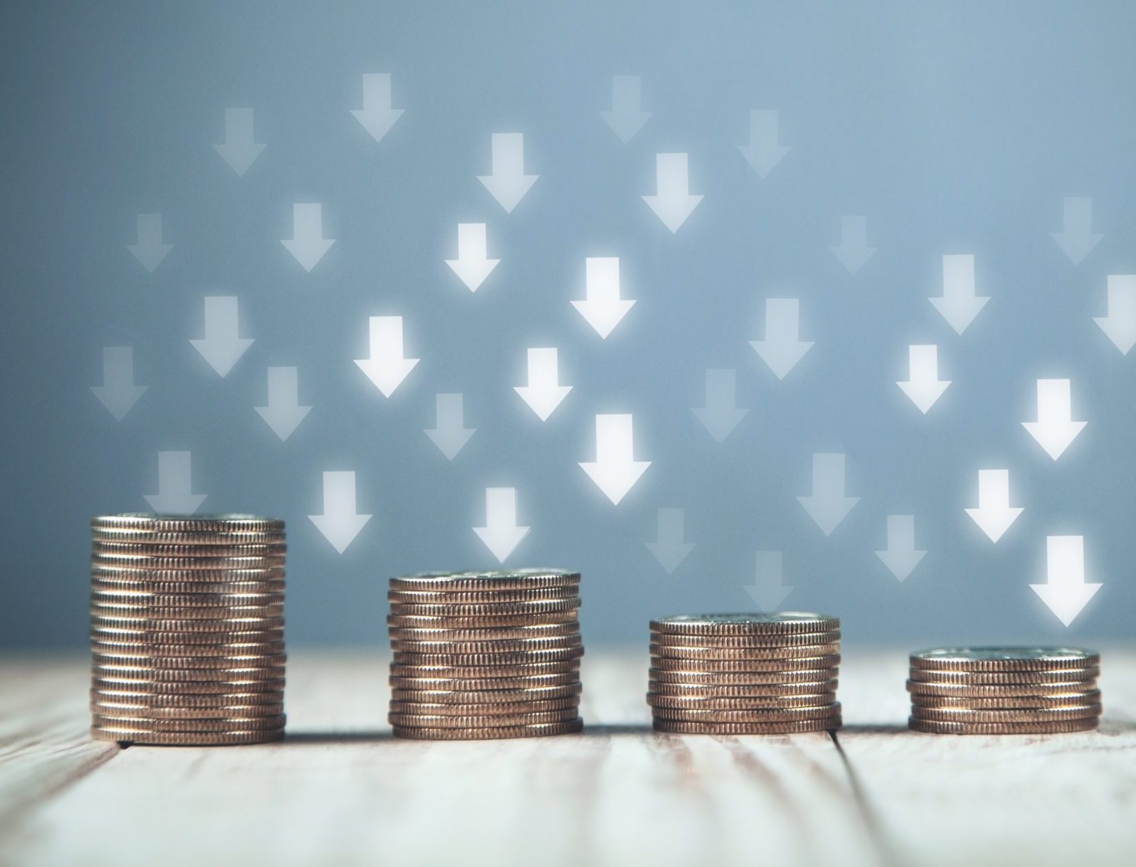 stacks of coins with arrows going down indicating telecom cost reduction
